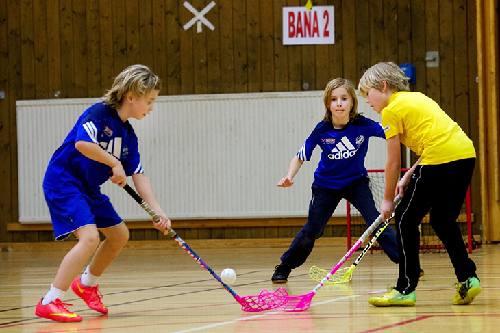 Tre barn som spelar innebandy.
